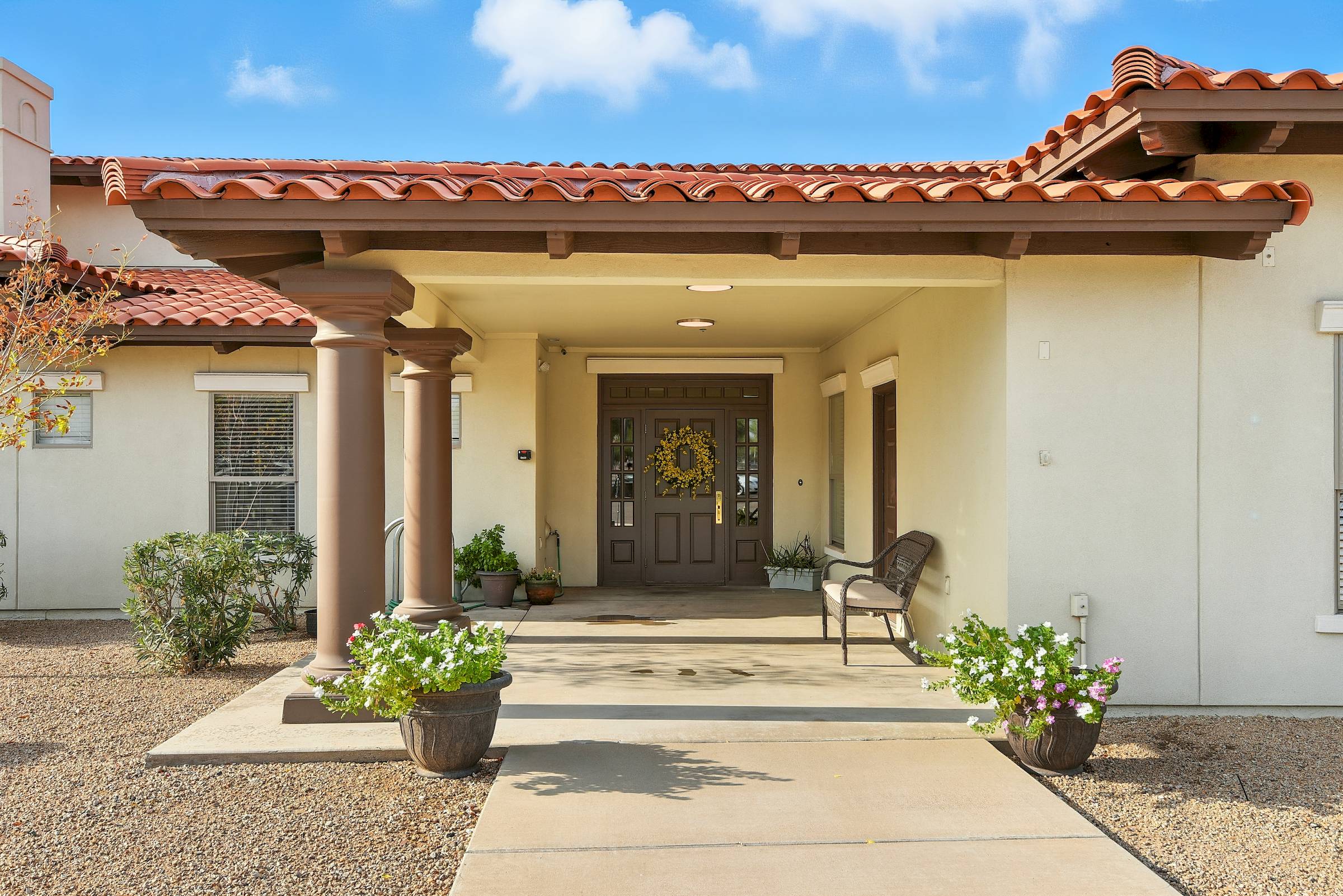 The front entrance of Barton House features a wreath on the door, a bench, potted plants, and a charming covered porch.