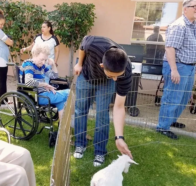 A resident visiting with a small animal on the lawn at Barton House