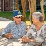 Show photo 15: Two residents enjoying the courtyard by the pond