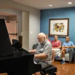 Show photo 91: Residents gathered around the piano
