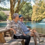 Show photo 17: Residents at a picnic table by the pond and fountain