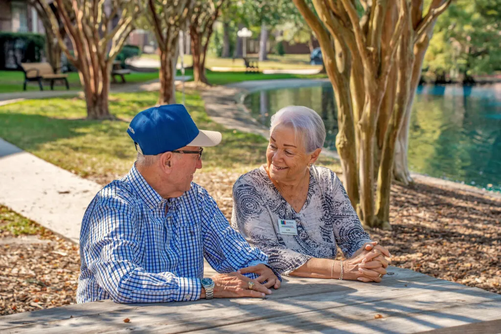 Two residents talking at a picnic table by the pond