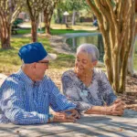 Show photo 13: Two residents talking at a picnic table by the pond