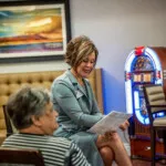 Show photo 82: A team member chatting with a resident by the jukebox