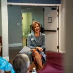 Show photo 94: A team member visiting with residents in the lounge