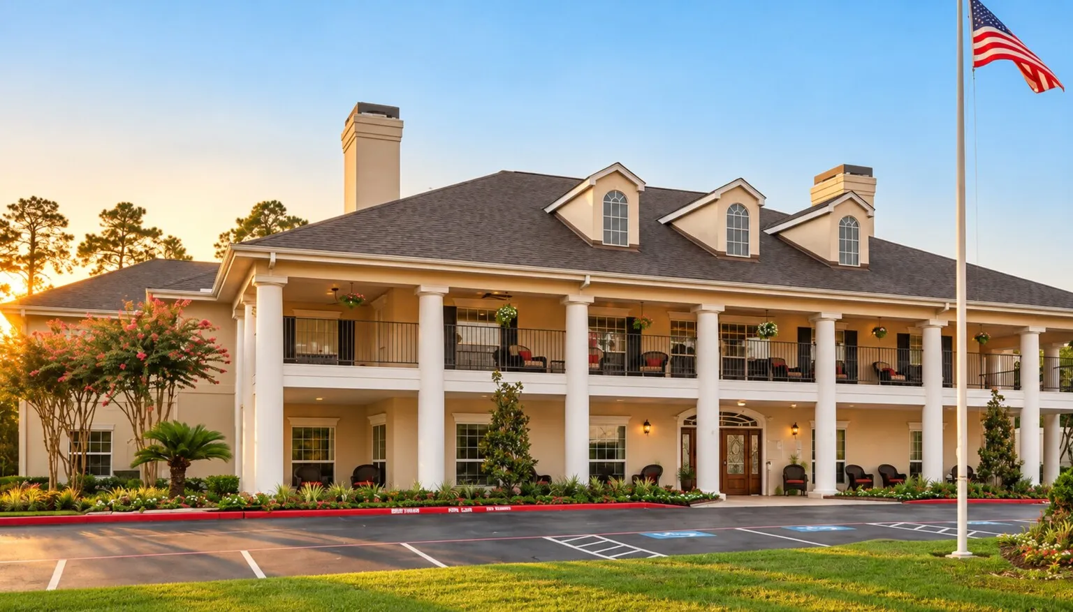 The two-story white-columned porch at Tarina of Cypresswood with the flag out front at sunset